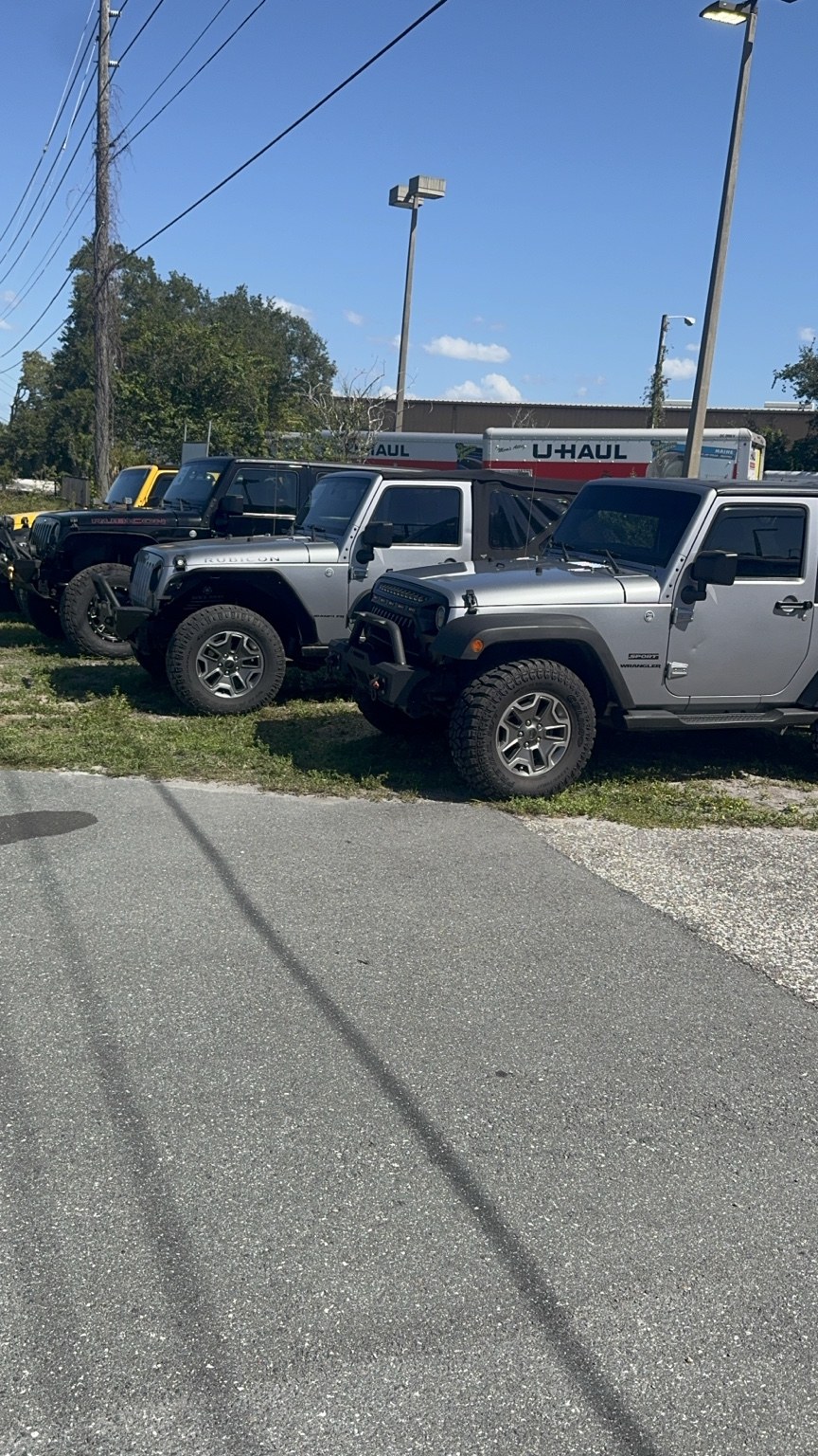 A row of Jeeps at Renown Automotive with U-Haul trucks behind them